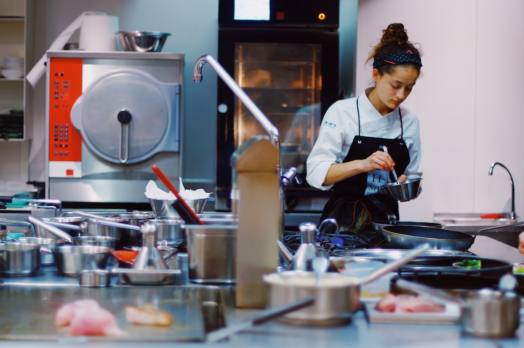 female chef cooking in back of restaurant kitchen